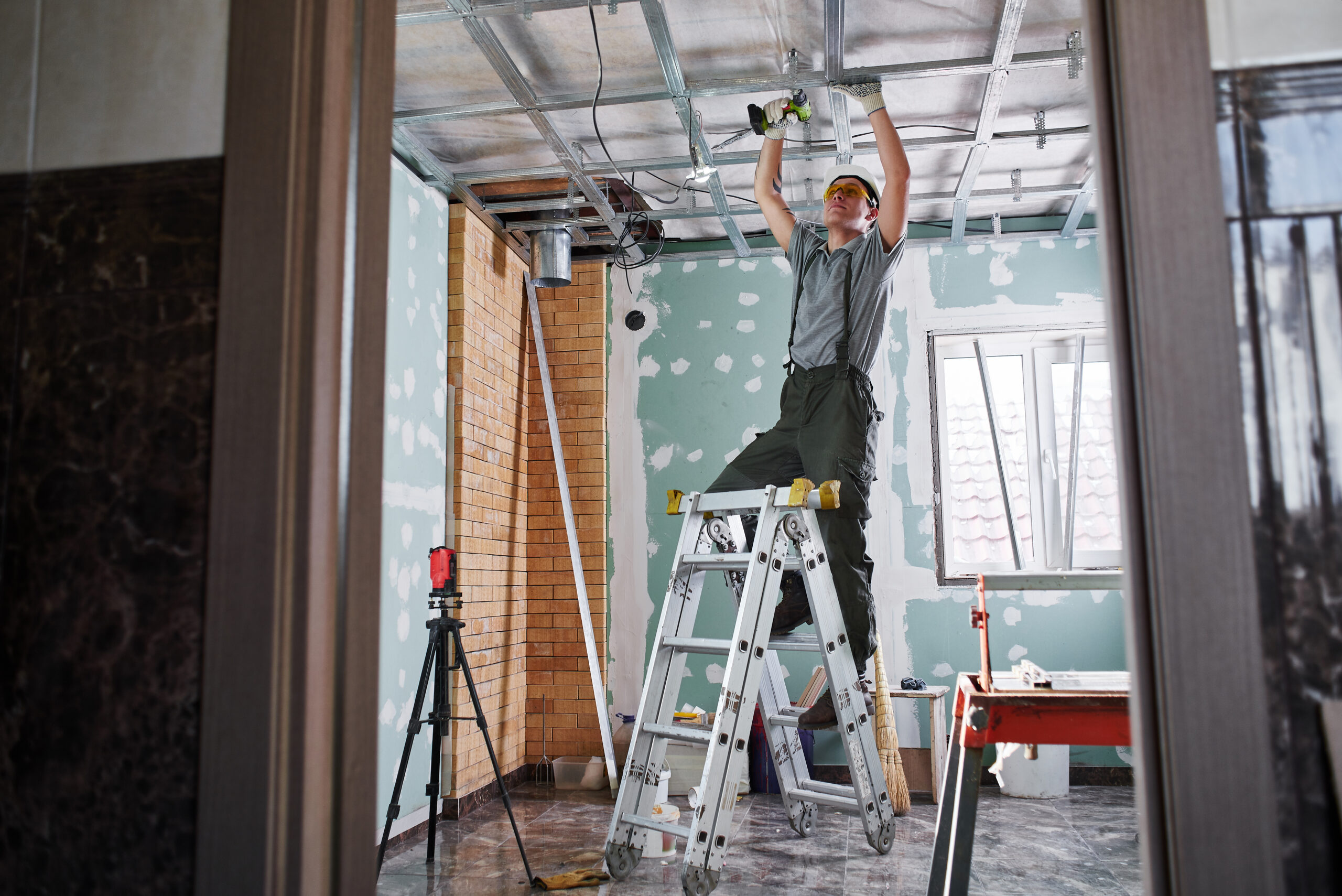 Room repair. Interior finish. young builder makes a plasterboard ceiling, standing on a stepladder